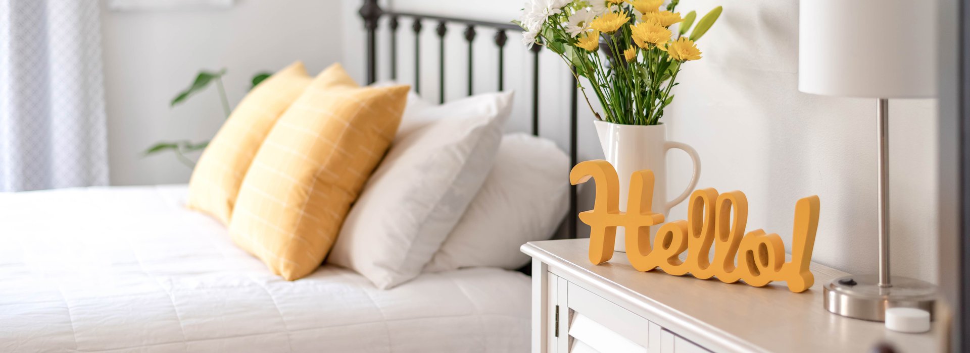 Cheerful-hello-sign-in-clean-and-bright-bedroom-with-yellow-accents